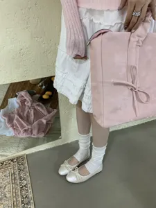 Primo piano di scarpe basse eleganti da donna con fiocco delicato, perfette per abiti.