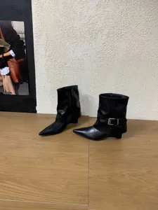 Detailansicht schwarzer spitzer Keilabsatzstiefel mit Schnalle und lockerem Schaftdesign.