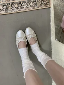 Dettagliato primo piano di scarpe basse da donna con un grazioso fiocco e calzini.