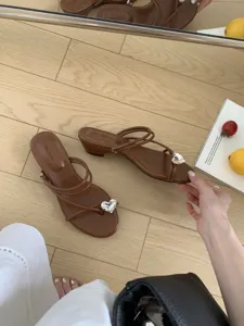 Gros plan de sandales marron à brides avec talon bas et strass en forme de cœur.
