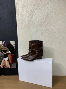 Detailaufnahme dunkelbrauner spitzer Keilabsatzstiefel mit stylischem Schnallenriemen.