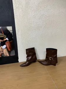 Detailansicht trendiger brauner Keilabsatz Stiefeletten mit spitzer Zehenpartie und Schnalle.