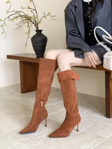 Detailopname van elegante bruine suède laarzen met hoge hak en een opgeslagen manchetontwerp.