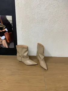 Detailaufnahme beige spitz zulaufender Schlupfstiefel mit seitlicher Schnalle und Keilabsatz.