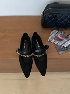 Nahaufnahme schwarzer spitzer Mary Jane Schuhe mit schicker Goldkette und Riemen.