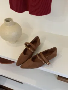 Detailaufnahme brauner, spitzer Mary Jane Schuhe mit schickem Kettengürtel und Wildleder.