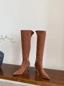 Gedetailleerd overzicht van bruine suède laarzen met spitse neus en elegante stilettohak.