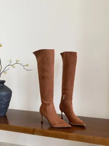Gedetailleerd overzicht van elegante bruine suède laarzen met hoge hakken en punt.