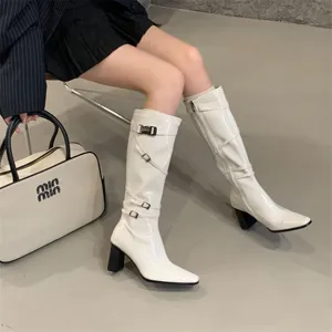 Vista detallada de botas altas blancas con tacon y hebillas para conjuntos de otono elegantes.