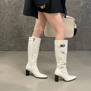Primer plano detallado de botas altas blancas con tacón grueso, punta y hebillas elegantes.