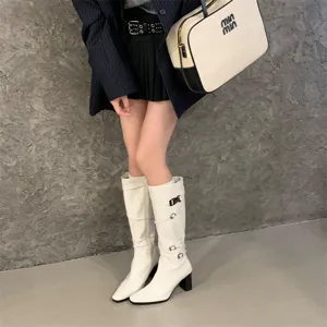 Botas altas blancas con puntera puntiaguda, tacón ancho y detalles de tiras con hebilla.
