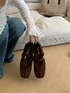 Gros plan de chaussures plates Mary Jane en daim marron élégant avec boucle en métal.