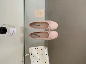 Detailansicht rosa Leder-Ballerinas mit niedlicher Schleife und feinem Wellenrand.