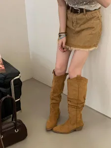 Gros plan de bottes western rétro avec bout pointu, tige plissée et talon épais confortable.