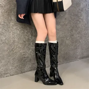 Vista detallada de botas altas y elegantes de charol negro con correas de hebilla.