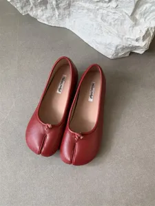 Detailed view of red soft leather split-toe flat shoes with comfortable insole and unique toe design.