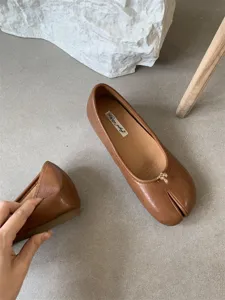 Detail view of brown split-toe soft leather flat shoes, minimalist daily casual footwear design.