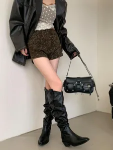 Gros plan de bottes hautes vintage plissées à bout pointu et talon épais pour femmes.