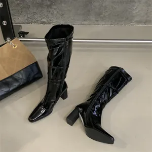 Detalle de botas altas de charol negro, punta cuadrada tacón ancho calzado de moda.