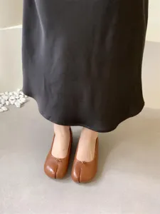 Brown leather split-toe flat shoes detail shot showcasing soft texture and unique design.