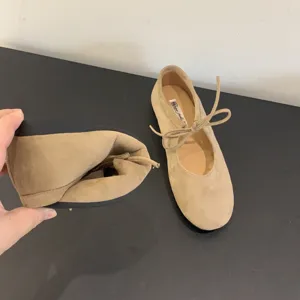 Soft beige leather lace-up ballet flats detail showing flexible sole and sweet bow knot.