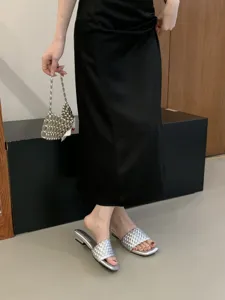Vista detallada de sandalias plateadas tejidas con tacón cuadrado bajo para mujer, estilo veraniego.