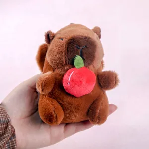Cute capybara plush toy pendant close-up, soft stuffed animal keychain with a red apple.
