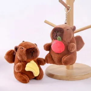 Cute capybara plush keychain toy holding apple and banana, soft stuffed animal doll pendant detailing.