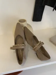 Detailaufnahme von spitzen Mary Jane Ballerinas aus taupefarbenem Wildleder mit goldener Kette.