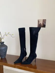 Close-up detail van zwarte suède laarzen met punt neus en hoge stiletto hakken.