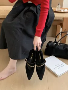 Detaillierte Nahaufnahme eleganter schwarzer Mary-Jane-Schuhe mit schicker Metallkette.