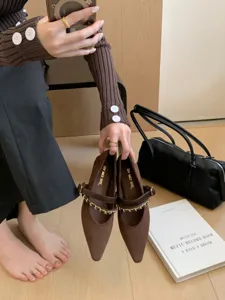 Detailansicht brauner spitzer Mary Jane Schuhe mit schickem Metallketten-Riemen.