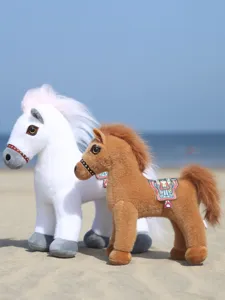 Vue détaillée de mignons chevaux en peluche de simulation avec selle et crinière sur la plage.