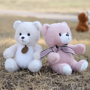 Bella foto di dettaglio di orsacchiotto di peluche, morbido giocattolo con nastro e ciondolo bimbi.