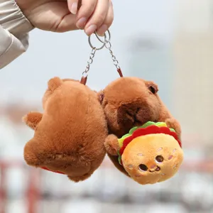 Close-up detail shot of the cute capybara plush toy holding a burger keychain accessory.