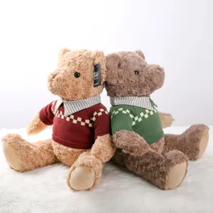 Detailed view of two cute vintage sweater teddy bear plush toys sitting back to back together.