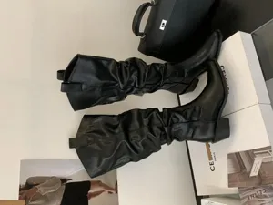 Détail de bottes souples noires à bout pointu, talon épais, tige haute, style western de chevalier pour femmes.