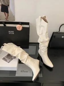 Vue détaillée de bottes western beiges froncées à bout pointu et talon large dans un décor chic.