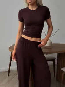 Detail view of a brown knit short sleeve top and pants set in a modern indoor setting.