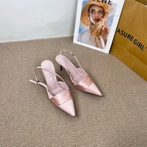 Detail view of pink satin pointed toe slingback stiletto high heels shoes on carpet surface.