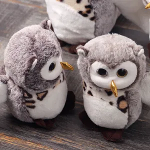 Close up view of cute grey owl plush toy with soft texture and golden beak on textured background.