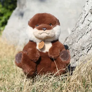 Detailed outdoor close-up view of a realistic brown otter plush toy resting on grass.