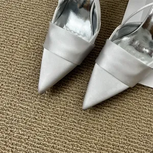 Detail view of silver satin pointed-toe high heels, elegant fairy style women shoes.
