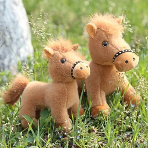 Outdoor detailed view of cute brown plush pony toys in grass, soft stuffed animal set.