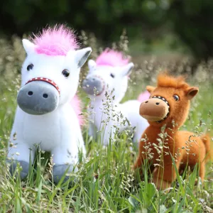 Detailed shot of cute plush pony toys featuring soft fur and realistic bridles in outdoor grass.