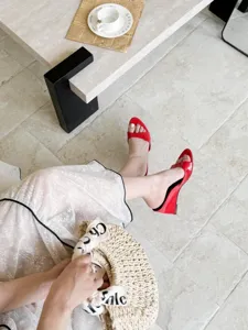 Close-up detail of stylish red patent leather wedge open-toe sandals, elegant summer vibe.