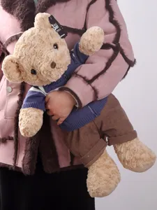 Detail shot of cute curly fur teddy bear with blue sweater and brown trousers, soft huggable plush toy.