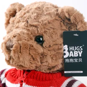 Cute brown plush teddy bear toy wearing a soft red and white knitted sweater detail view.