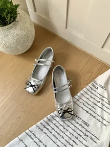 Silver metallic Mary Jane shoes for women featuring double straps and cute bows. Detail shot.