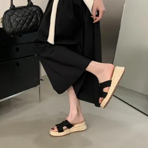 Nahaufnahme Detailansicht schwarzer Damen Keilsandalette mit geflochtener Bastsohle.